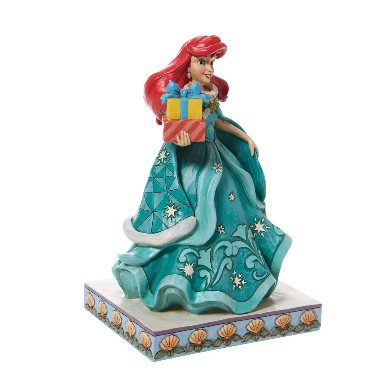 Jim Shore Ariel Little Mermaid with Gifts Figurine - Gifts of Song In a brilliant blue dress, Ariel is a vision of beauty and gratitude in this lovely Jim Shore statuette. Carrying gifts and wearing a broach of holly, the princess delivers presents to all those Under the Sea. Flounder and Sebastian grace the base. Hand painted and hand sculpted from high quality cast stone.