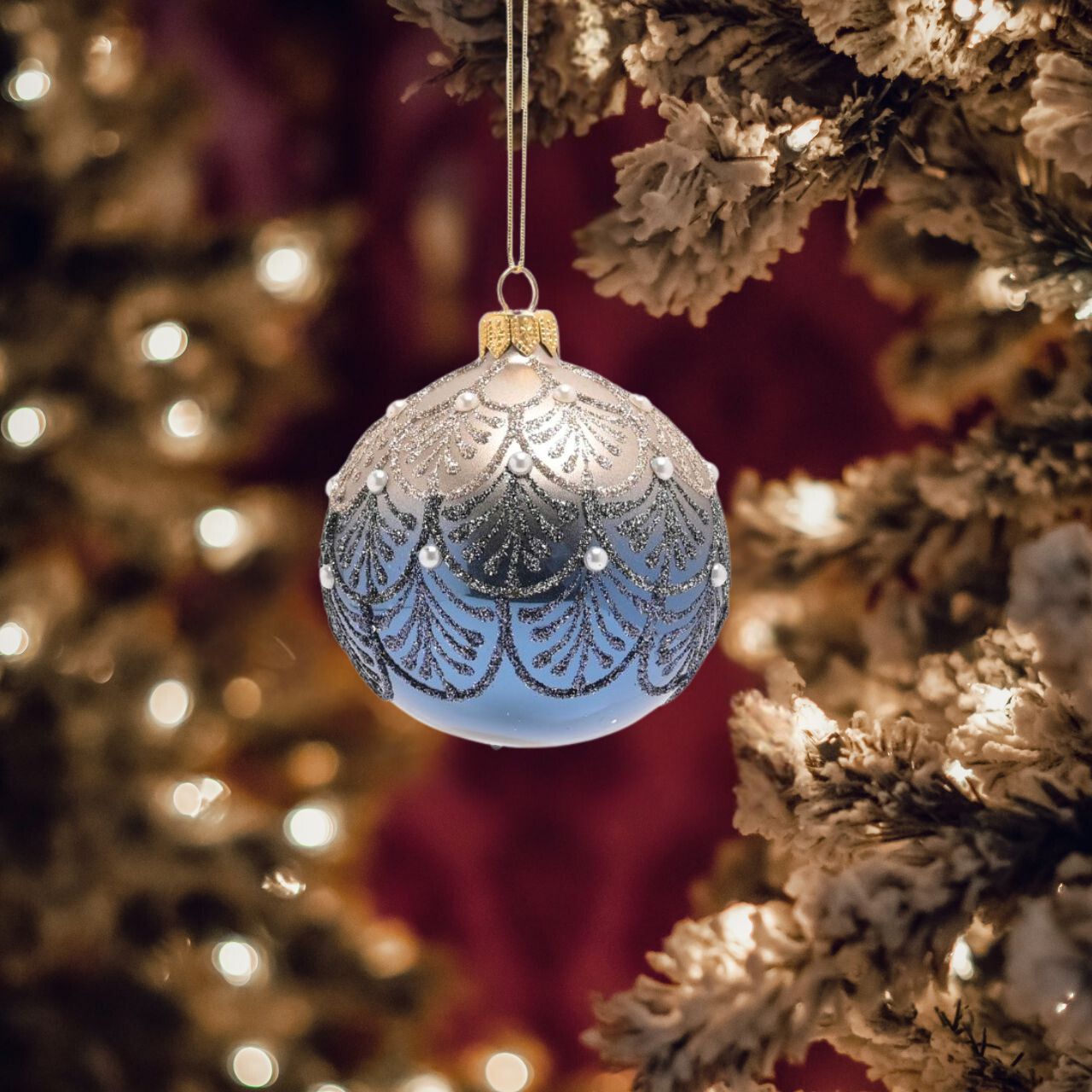 The glass bauble showcases attractive blue & silver colouring, complete with a hand decorated crystal design and shiny glitter finish. It is displayed on the tree using its gold thread.