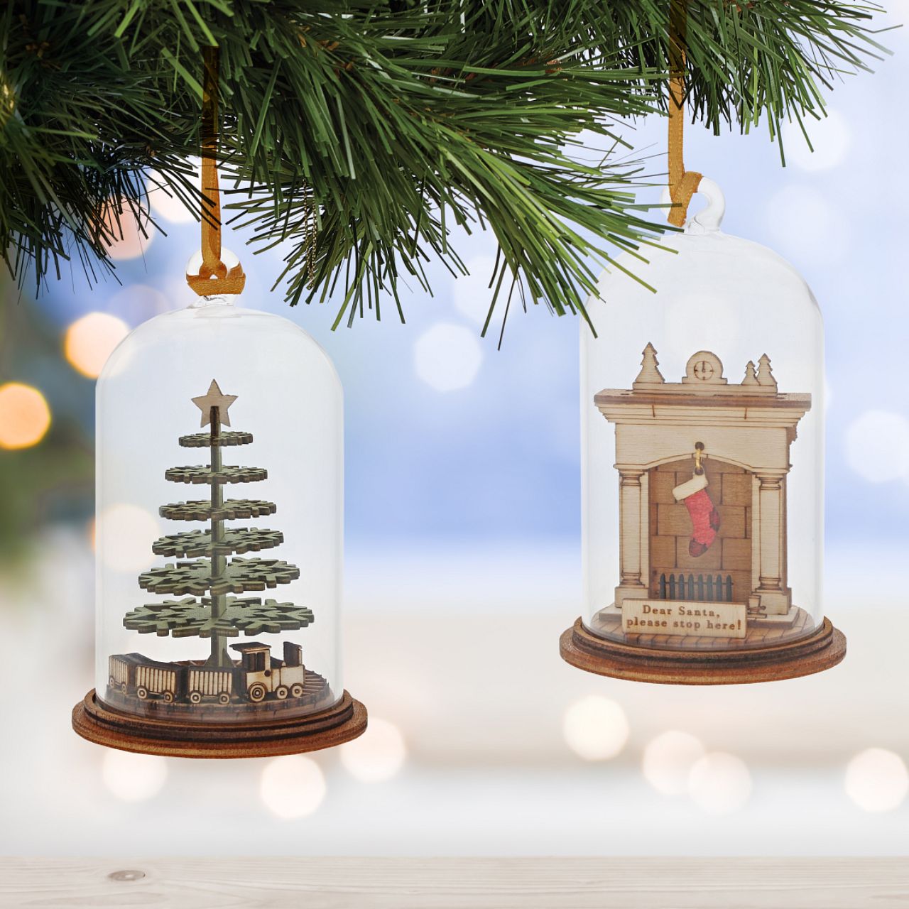 Christmas Childhood Memories Hanging Ornament Kloche The Spirit of Christmas. A collection of delightful wooden decorations that capture the essence of that special time of year. This glass dome, Christmas decoration encases a Christmas tree, adorned with a nostalgic train set and ribbon to help hang off your Christmas tree.