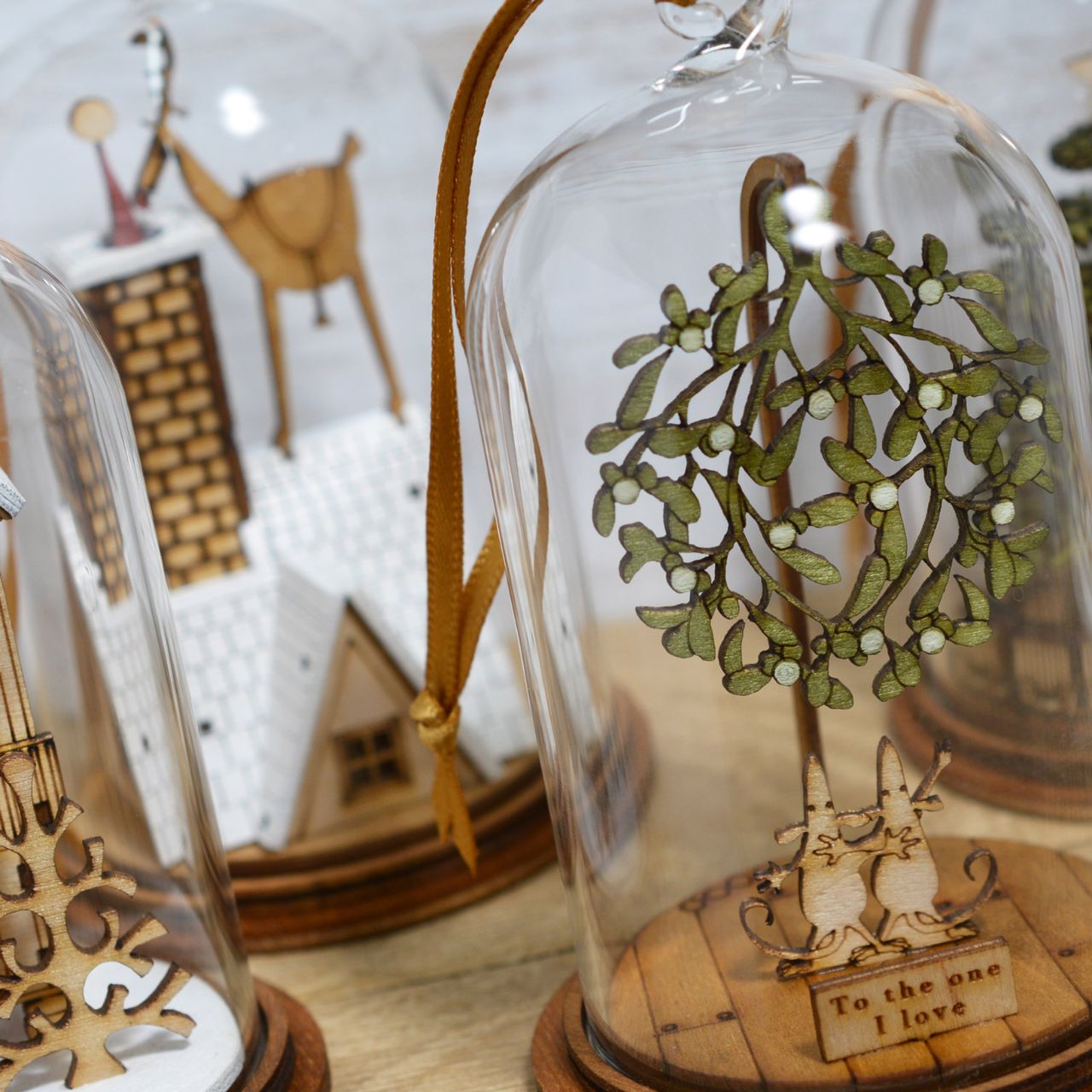 Christmas Eve Kloche Hanging Ornament The Spirit of Christmas. A collection of delightful wooden decorations that capture the essence of that special time of year. This glass dome, Christmas decoration encases a Reindeer helping Santa deliver presents, adorned with a ribbon to help hang off your Christmas tree.