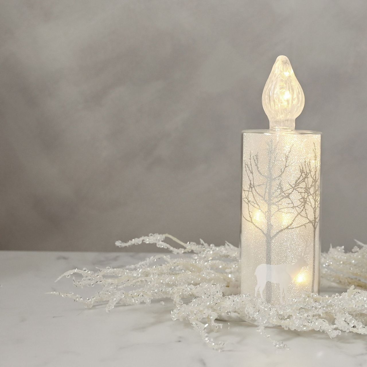 Christmas Silver Forest Scene Medium LED Glass Candle Light A medium silver forest scene LED candle-shaped light by THE SEASONAL GIFT CO. This glistening light will help to create a magical Winter Wonderland at home this festive period.