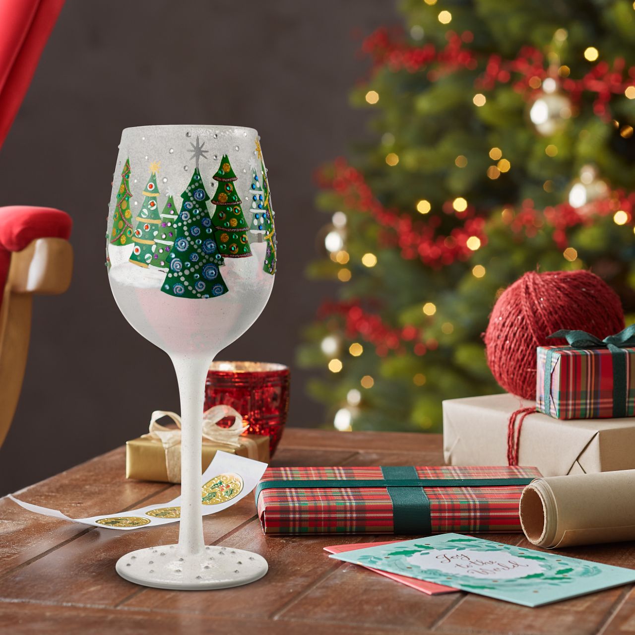 Christmas Trees in the Snow Wine Glass by Lolita  Christmas pines covered in lights and ornaments cover this winter wonderland wine glass. With textured snow and glittering accents, this wine glass is ready for wassail and snowflakes.
