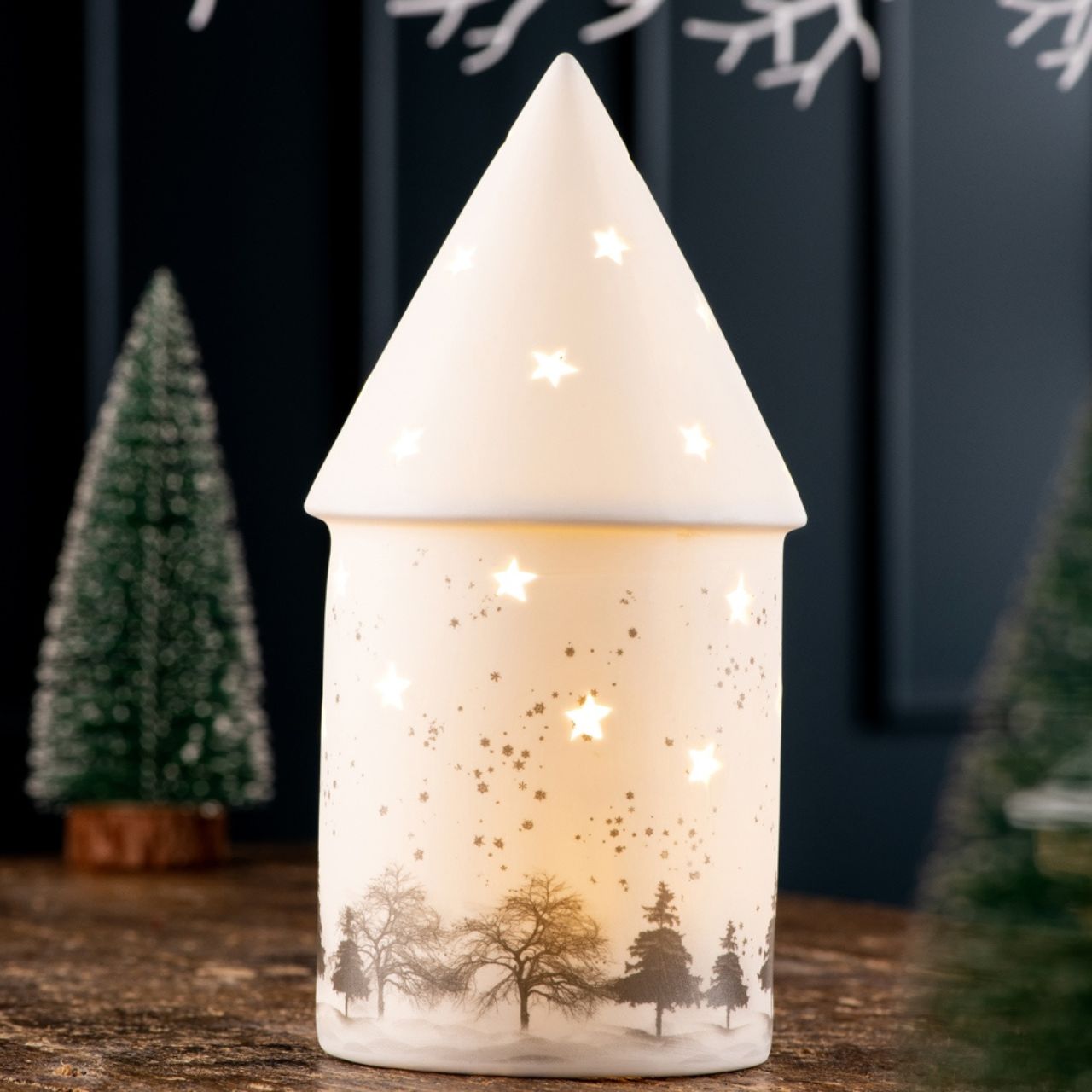 Christmas Winter Scene LED by Belleek Living The Winter Scene LED features delicately printed silhouettes of trees, rolling snow hills and falling snowflakes to create the quintessential winter scene. The star shaped piercings emit light and cast shadows creating the perfect ambient mood lighting for a cozy winter evening.