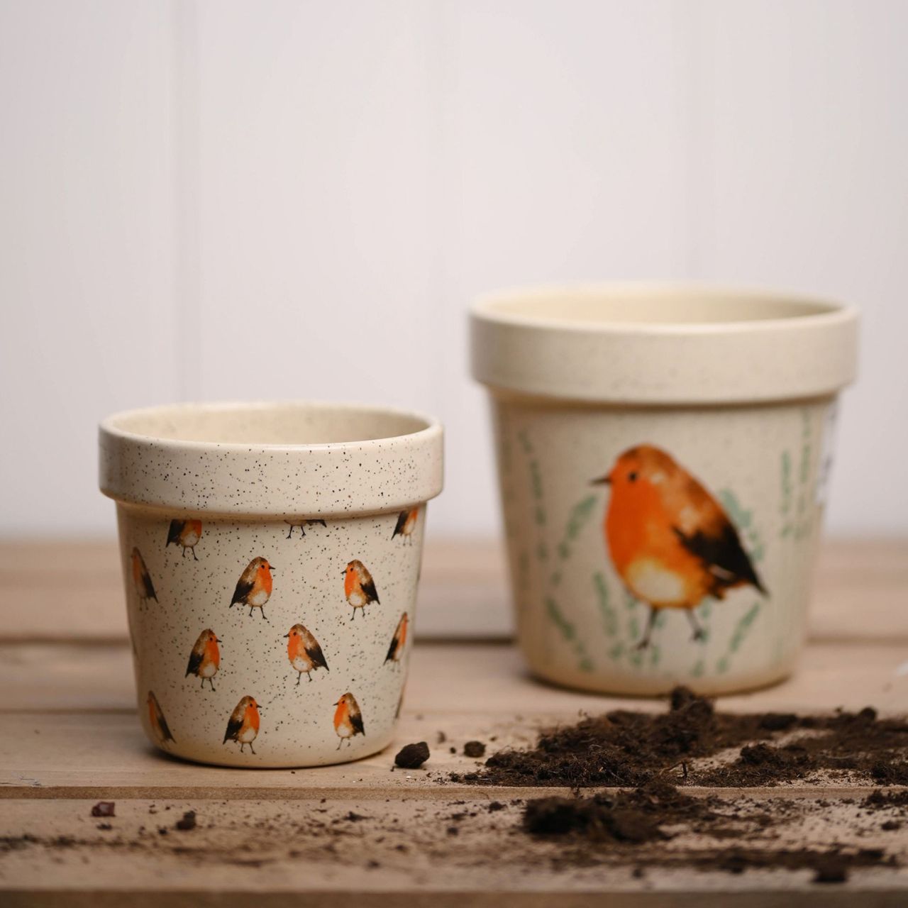 Country Living Set of 2 Planters - Robin A set of 2 decorative planters by COUNTRY LIVIING The ceramic duo showcases 2 different designs, the smaller having an all over Robin pattern on a speckled finish. The larger has two decorative images of a Robin, on a speckled cream surface.