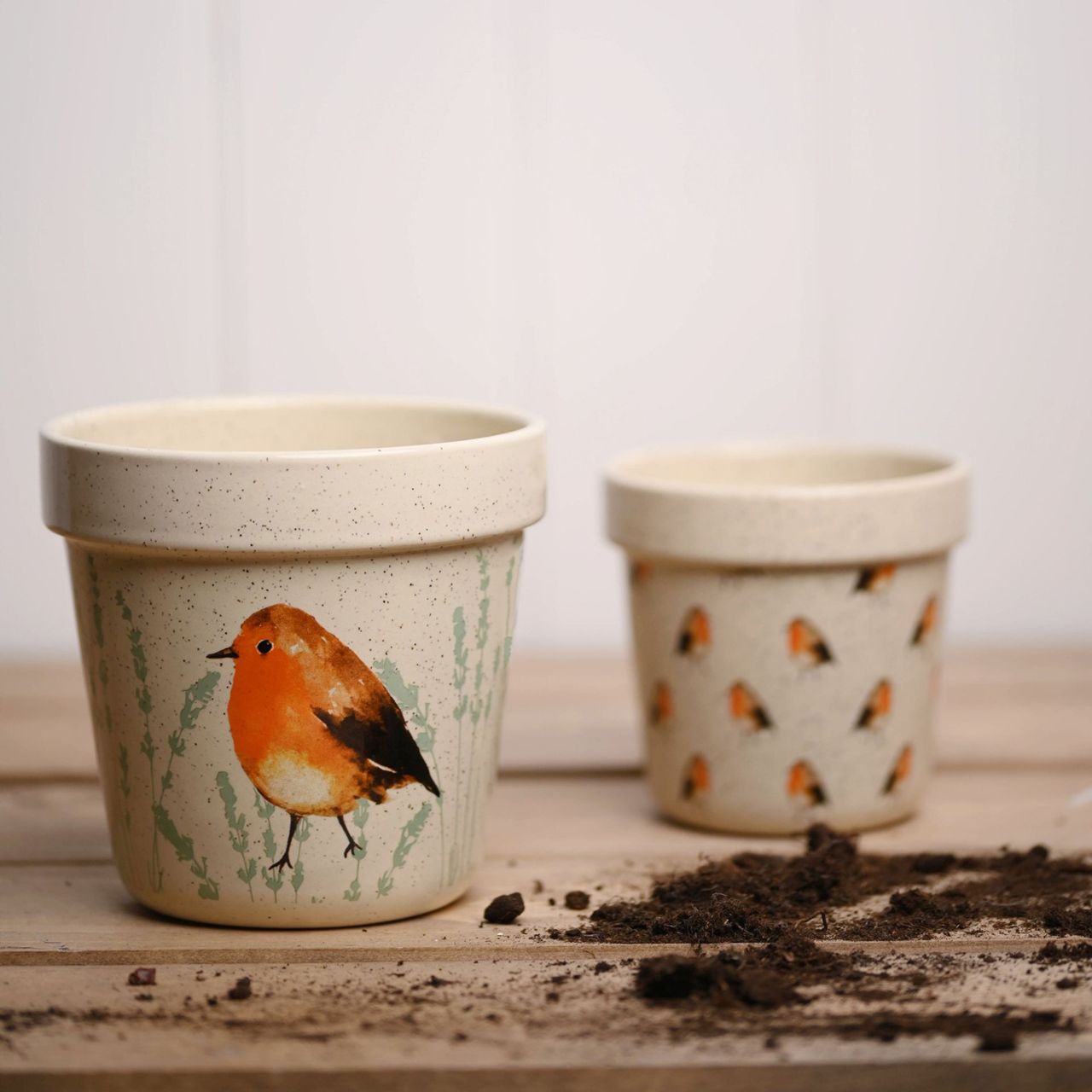 Country Living Set of 2 Planters - Robin A set of 2 decorative planters by COUNTRY LIVIING The ceramic duo showcases 2 different designs, the smaller having an all over Robin pattern on a speckled finish. The larger has two decorative images of a Robin, on a speckled cream surface.