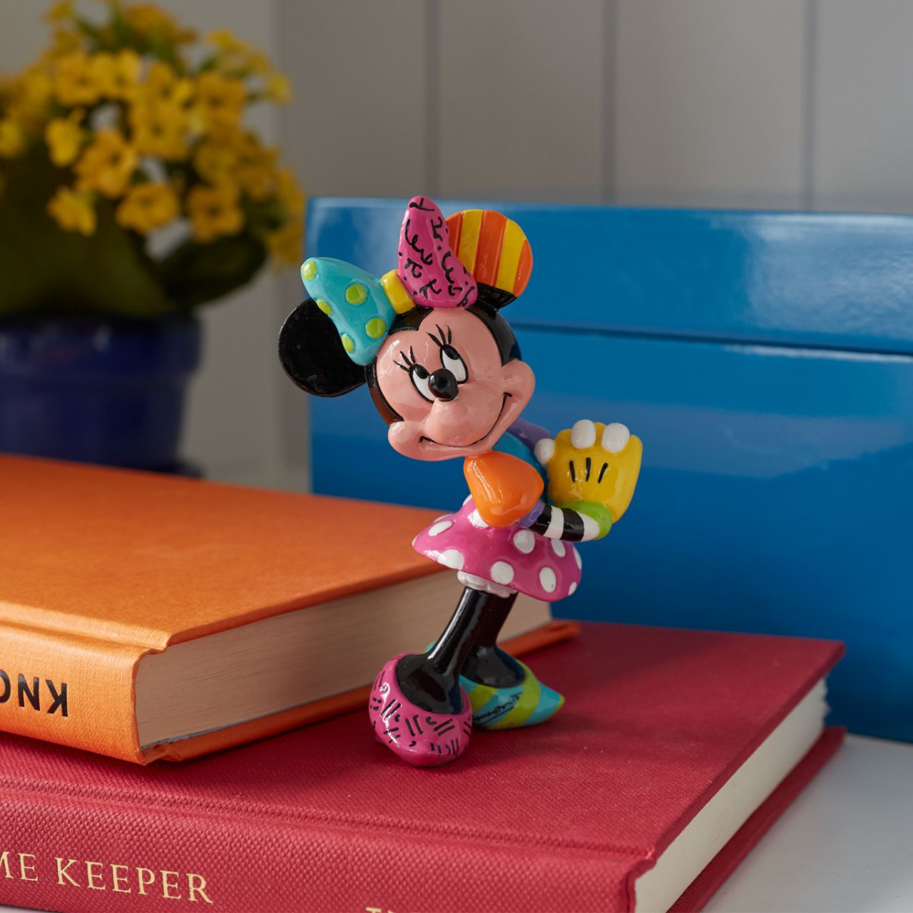 Blushing and smiling, Minnie eagerly awaits a gift from her beloved Mickey. Minnie Mouse is garbed in a beautiful rainbow of colours and patterns, compliments of a special paint job by Romero Britto, a multi-talented Brazilian pop artist.
