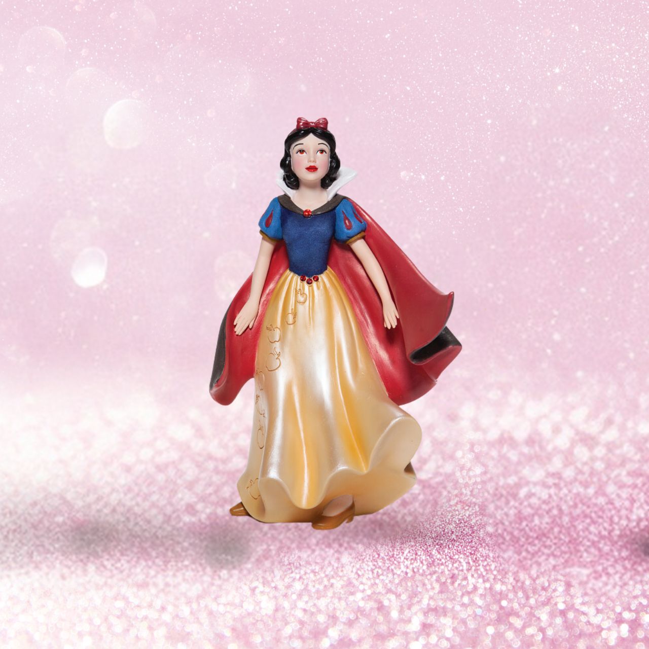 Snow White Couture de Force Figurine  Snow White with her skin fair as snow and lips red as apples follows the wind on a new adventure fit for a princess. Hand-crafted and hand-painted, her iconic outfit shimmers in yellow satins and dark wool felts plussed with red faux gem stones.