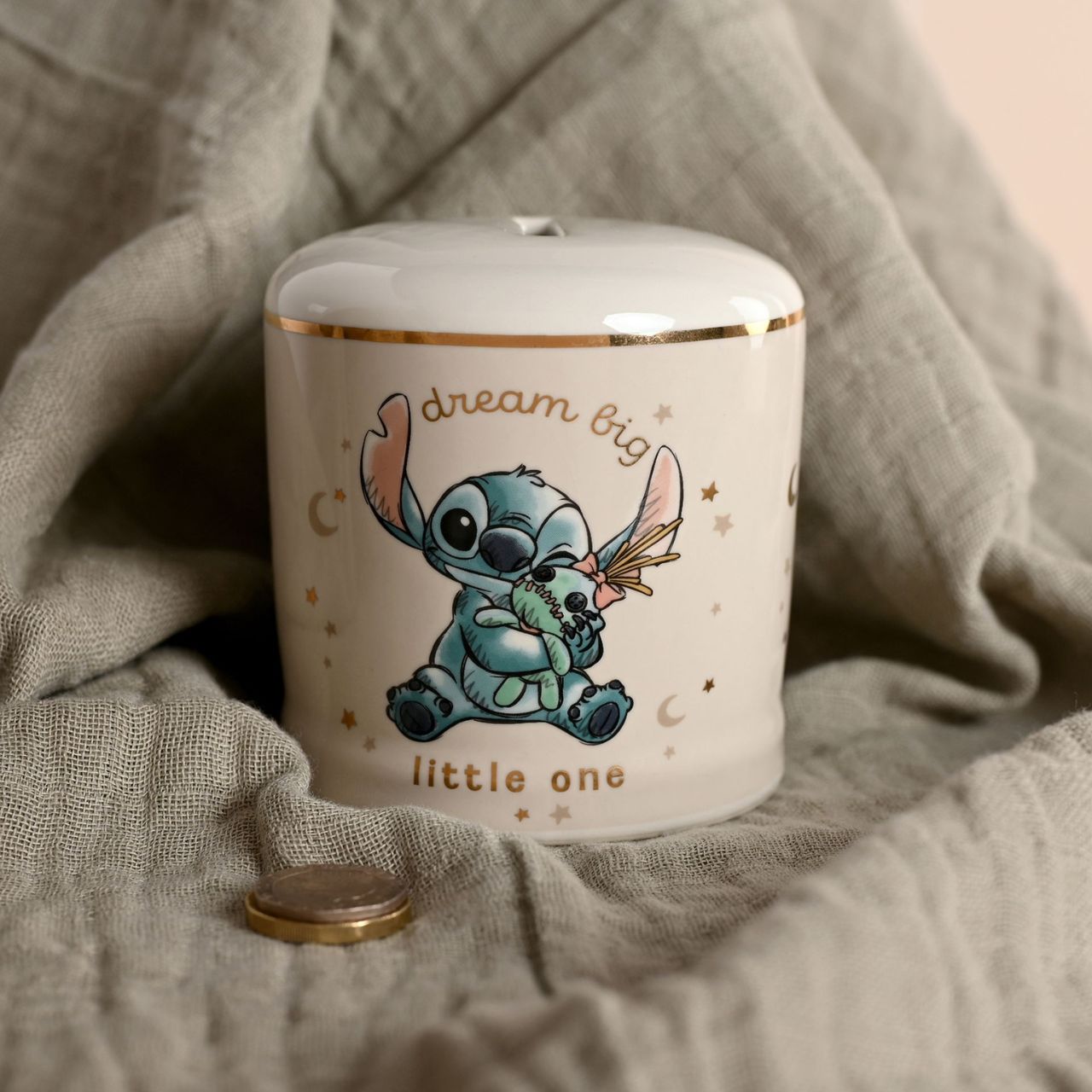 Ceramic jar with cartoon character and 'dream big little one' text on a soft fabric background