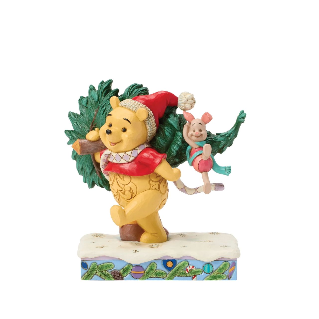 In this delightful Jim Shore scene, Winnie the Pooh sports intricate rosemaling and a Santa hat adorned with holly as he joyfully carries home a Christmas tree with Piglet in tow. They march through the snow on a festive stage of ornaments.