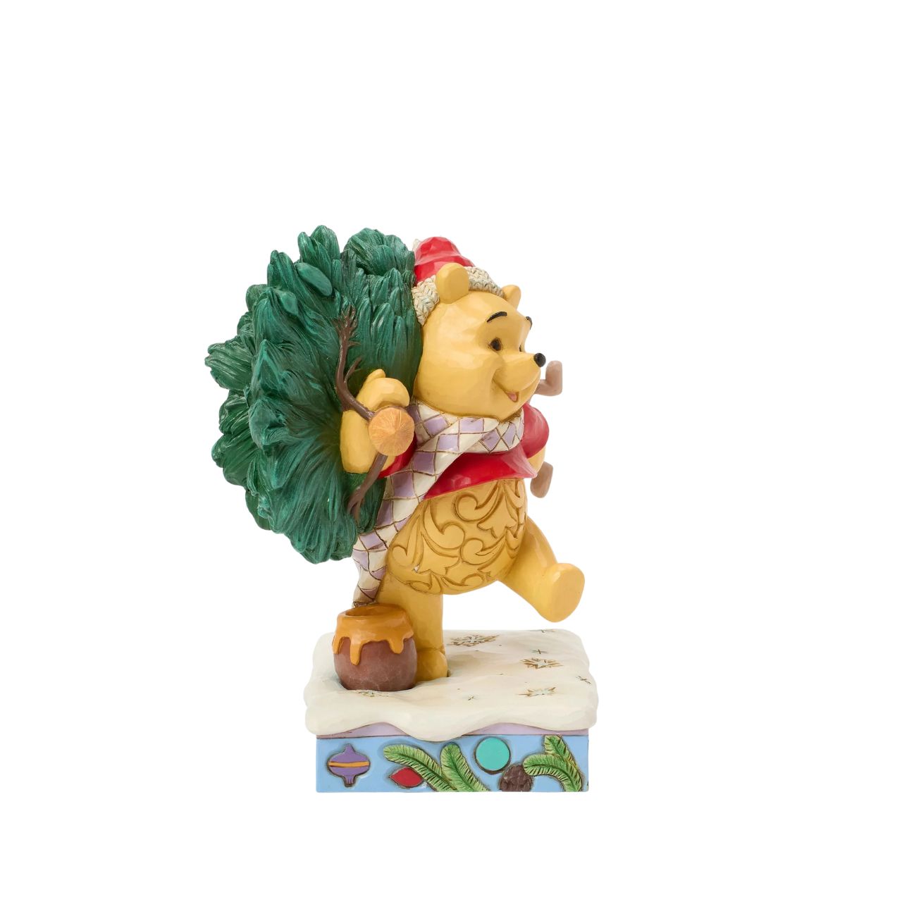 In this delightful Jim Shore scene, Winnie the Pooh sports intricate rosemaling and a Santa hat adorned with holly as he joyfully carries home a Christmas tree with Piglet in tow. They march through the snow on a festive stage of ornaments.