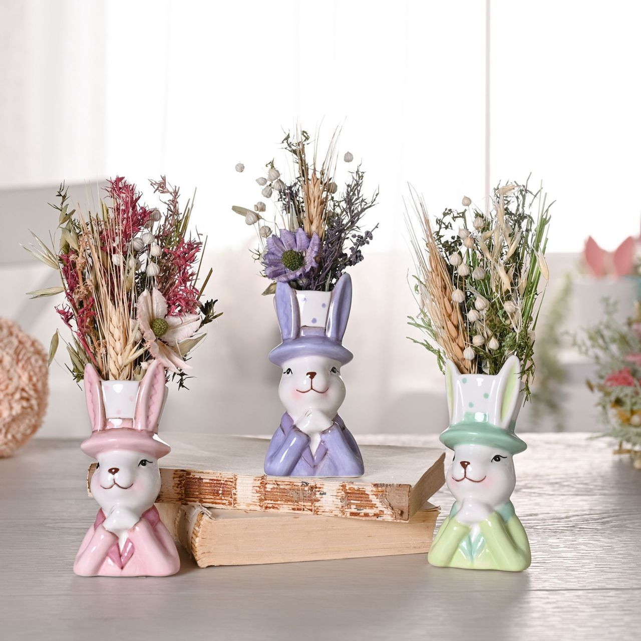 Bring a playful touch to your product line with the Eggs-traordinary Gifting Company's set of three Bunny in Top Hat Planter's Featuring adorable bunnies in three pastel colours, pink, purple and green. This charming set of planters adds a whimsical flair on their own and even more vibrancy when paired with plants or flowers.