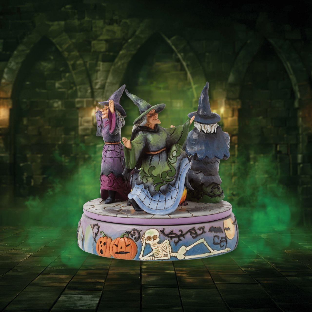 Enter the world of Halloween with this hand-touch rotation Jim Shore movement figurine featuring two witches dancing around a bubbling cauldron. Adorned with jack-o-lanterns, skeletons, tombstones, spiders, snakes, black cats, and bats, it's a bewitching scene.