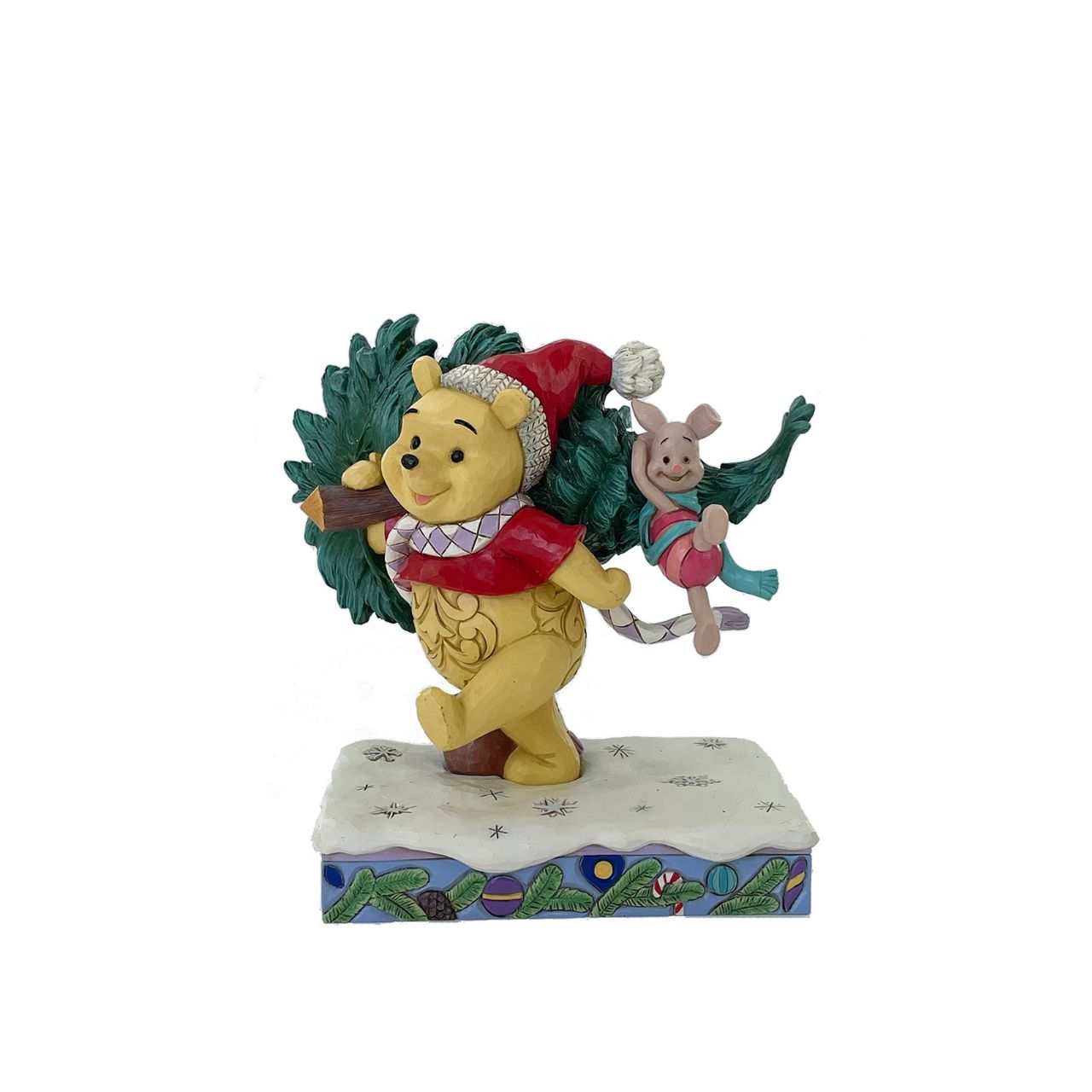 In this delightful Jim Shore scene, Winnie the Pooh sports intricate rosemaling and a Santa hat adorned with holly as he joyfully carries home a Christmas tree with Piglet in tow. They march through the snow on a festive stage of ornaments.