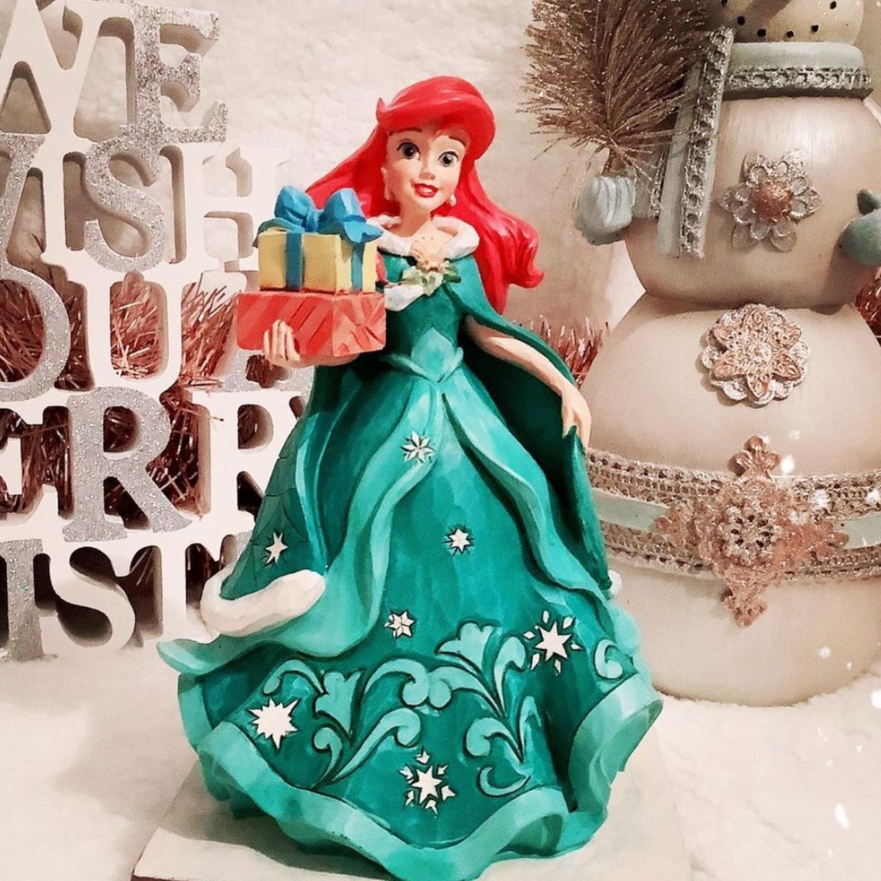 Ariel Little Mermaid with Gifts Figurine - Gifts of Song In a brilliant blue dress, Ariel is a vision of beauty and gratitude in this lovely Jim Shore statuette. Carrying gifts and wearing a broach of holly, the princess delivers presents to all those Under the Sea.