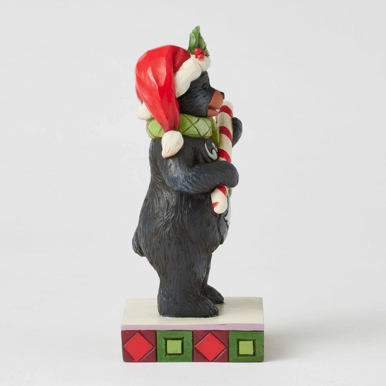 This playful Christmas at the Lodge Jim Shore black bear wears a festive Santa hat adorned with holly, he wears a festive scarf and holds a candy cane in his paws. With rosemaling designs on his fur, the piece brings sweet holiday fun and rustic charm to to any display.