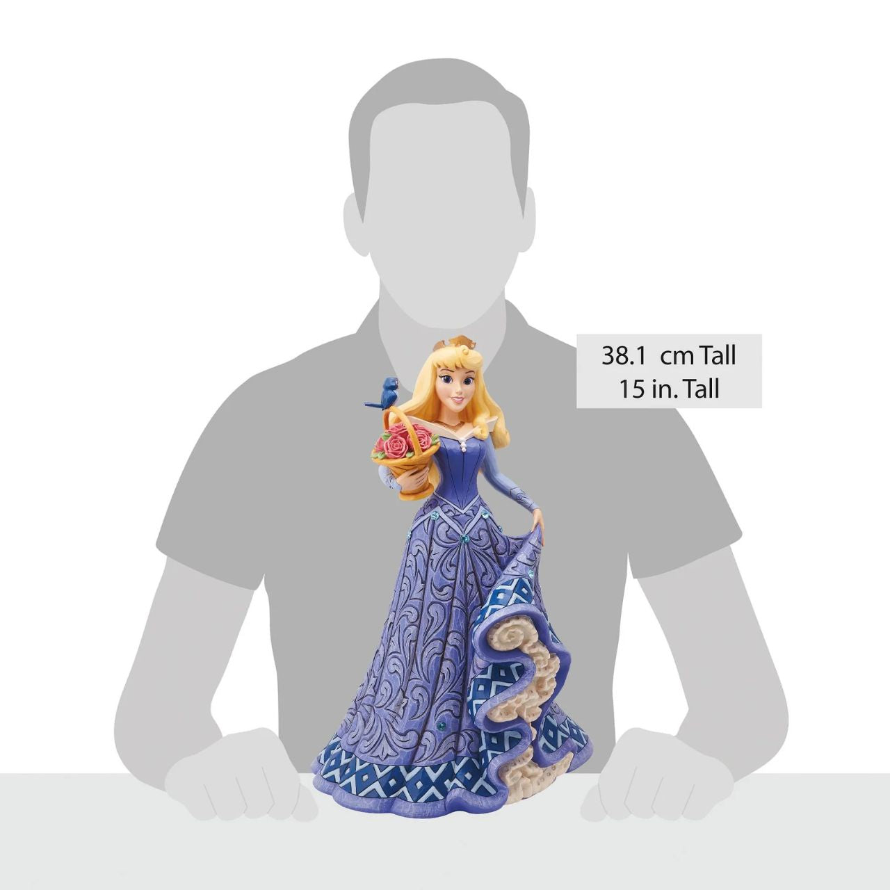 Introducing the Deluxe Aurora Figurine from Disney Traditions by Jim Shore. This exquisite piece depicts Sleeping Beauty Aurora in a beautiful, blue dress, accessorized with a stunning crown, carrying a basket of pink roses with a small bluebird perched on top.