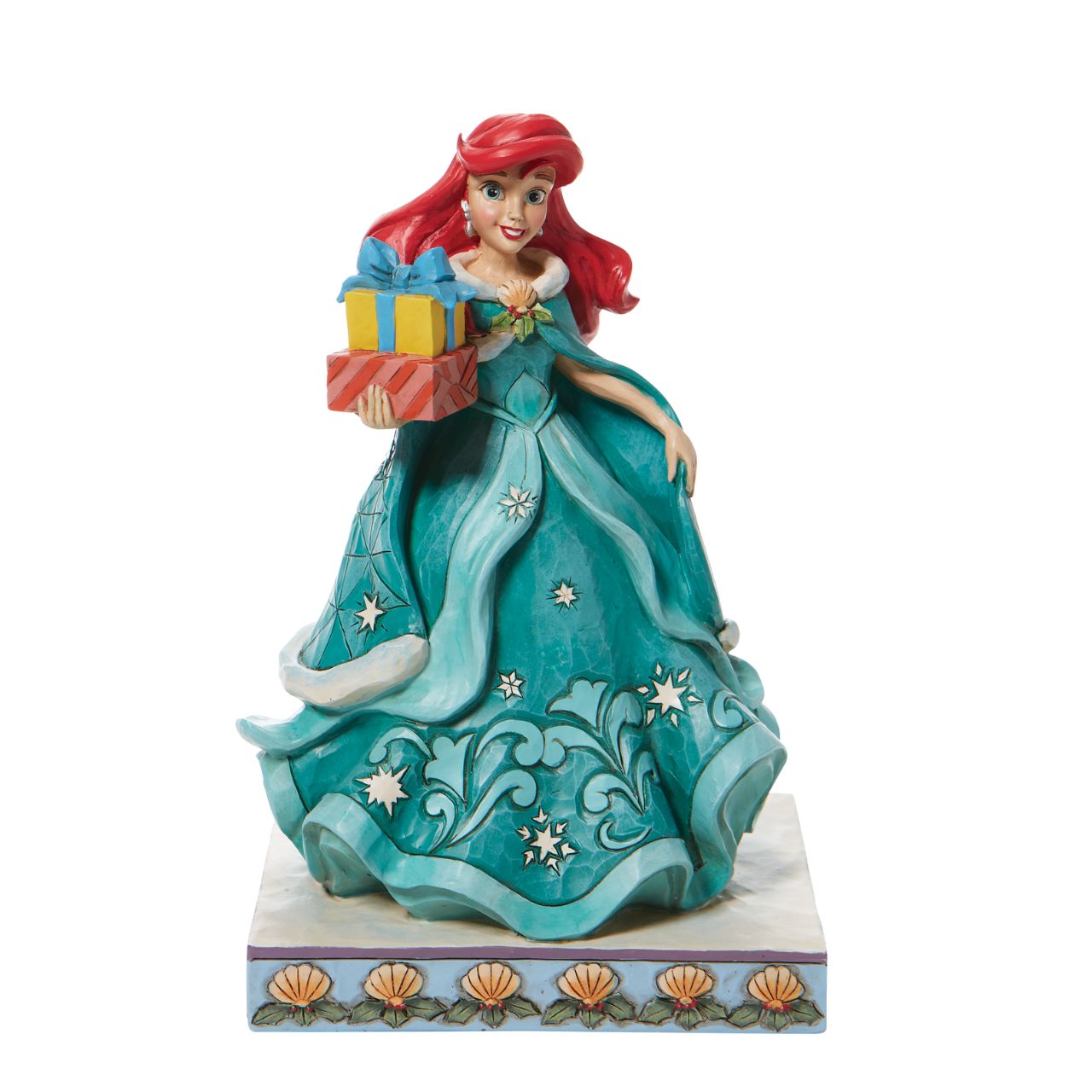 Jim Shore Ariel Little Mermaid with Gifts Figurine - Gifts of Song In a brilliant blue dress, Ariel is a vision of beauty and gratitude in this lovely Jim Shore statuette. Carrying gifts and wearing a broach of holly, the princess delivers presents to all those Under the Sea. Flounder and Sebastian grace the base. Hand painted and hand sculpted from high quality cast stone.