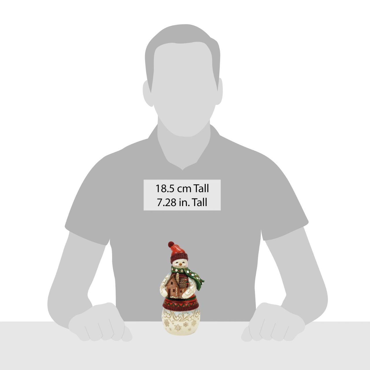 This Christmas at the Lodge Jim Shore snowman is dressed in an intricate red and green tunic and holds a little log cabin. With a knit cap, rosy cheeks, and a joyful smile, he glows with rosemaling and snowflakes, bringing festive warmth and cosy cabin vibes.