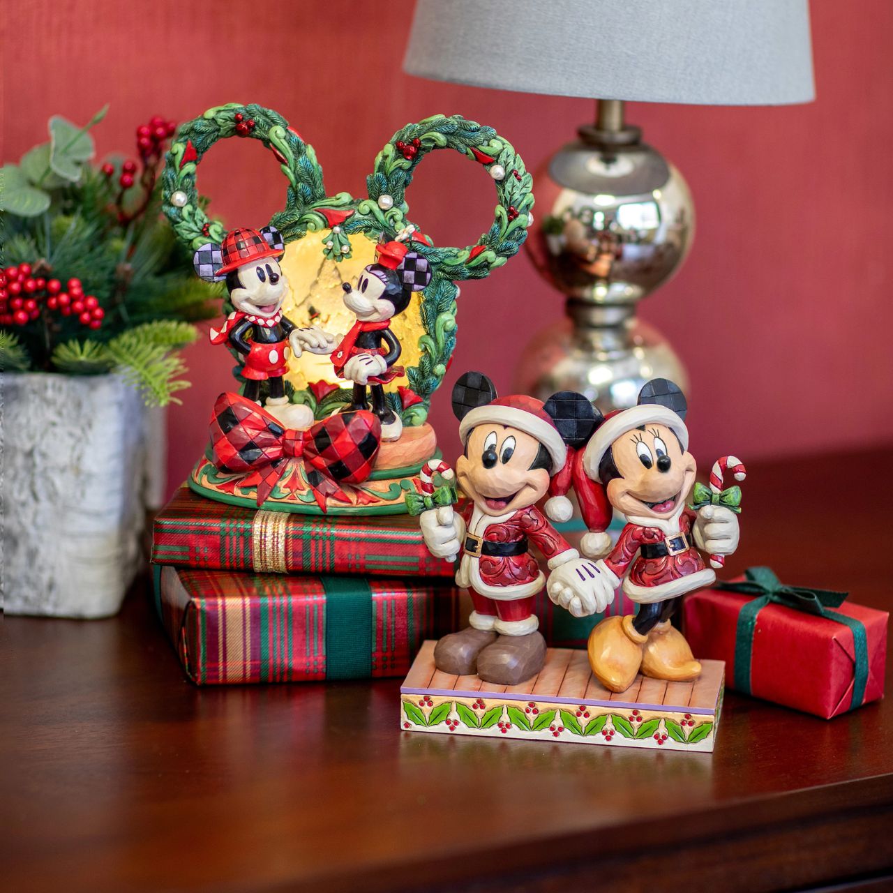 In this festive Jim Shore scene, Mickey and Minnie Mouse don Santa suits adorned with intricate rosemaling patterns and joyfully carry candy canes. Their bright smiles radiate holiday cheer, making the scene a delightful celebration of the season.