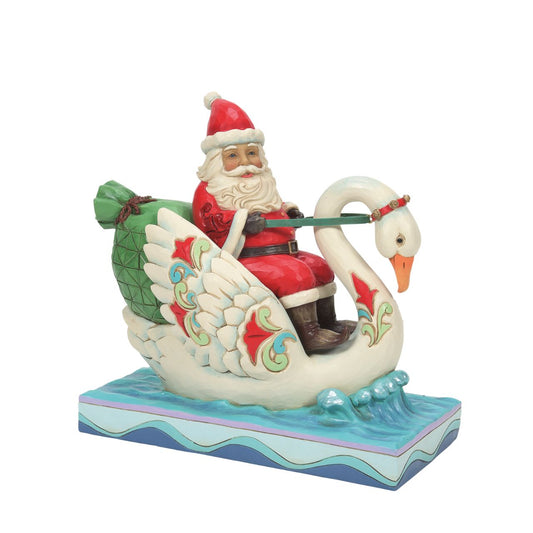 Heartwood Creek Santa Riding a Swan Figurine "Grace and Goodwill"  Steering a stately swan through the water, Santa gives his reindeer led sleigh a break as he makes deliveries riverside. The 7" Jim Shore piece is lively with colour and Christmas creativity. Floating to a town near you, Santa brings grace on wings.