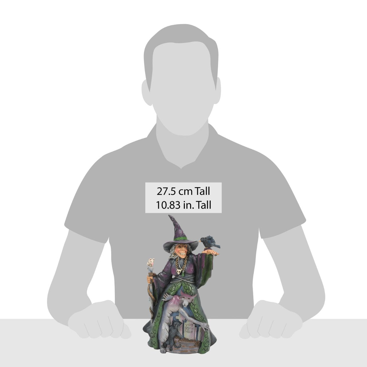 Enter the enchanting world of Halloween with this haunting Jim Shore witch figurine, adorned in ghastly purple and green robes, a perched crow and a staff with a slithering snake. Her cloak reveals a chilling graveyard scene with a spook and a black cat.