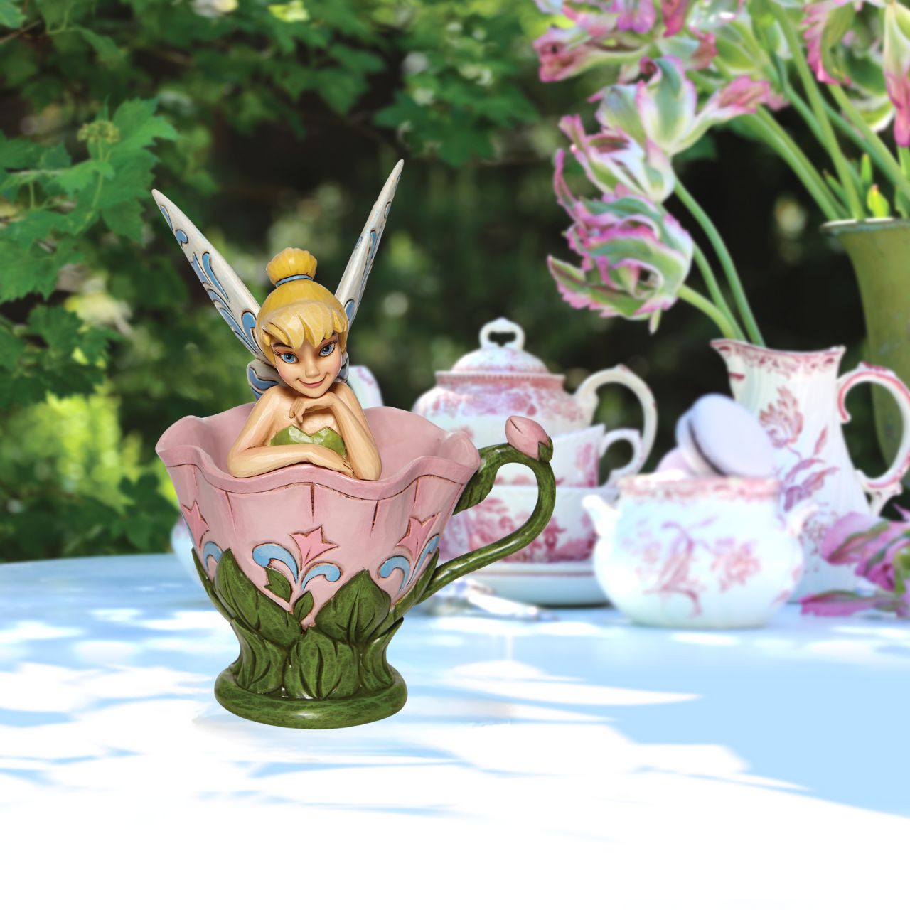 Disney Tinkerbell Sitting in a Flower Figurine A Spot of Tink by Jim Shore All the way from Neverland, this sweet and sassy fairy, takes a flower break before she's off on her next adventure. This Disney by Jim Shore piece is intricately hand sculpted and is great for any Tinker Bell enthusiast. Made from cast stone.