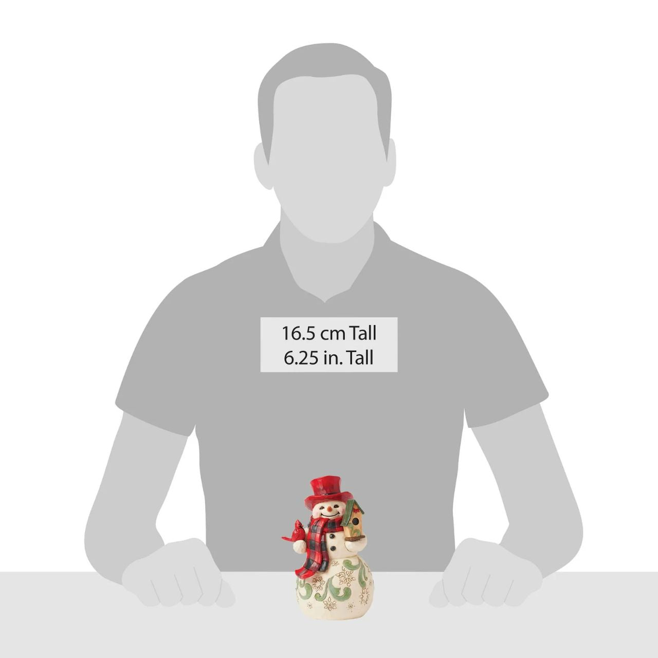 This whimsical Jim Shore Highland Glen snowman wears a cozy buffalo plaid scarf and a vibrant red top hat. Holding a charming birdhouse with a friendly cardinal perched beside him, his joyful smile radiates warmth and holiday spirit.