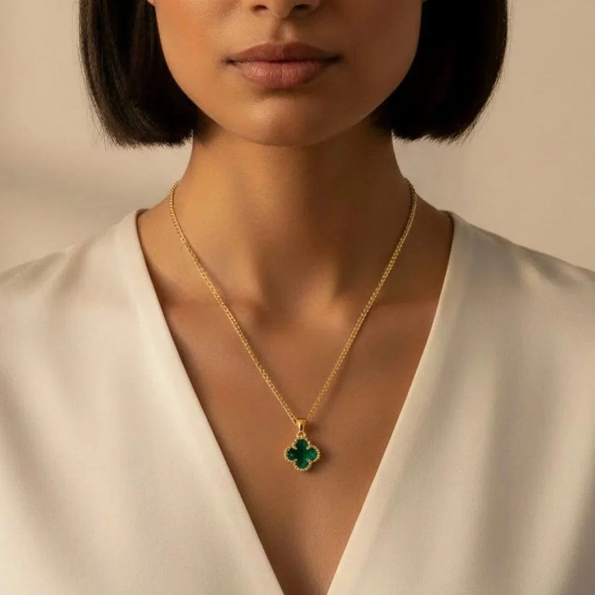 Elegant four-leaf clover pendant crafted from vibrant emerald crystal and set in gleaming gold plating.