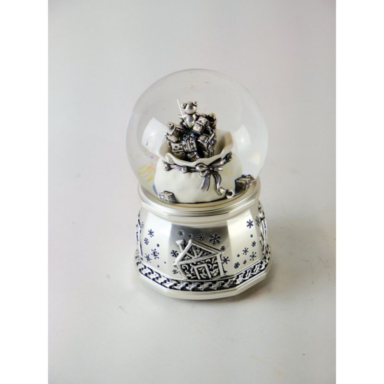 Silver coloured 100 mm snow globe with gift bag. After being wound up, the presents spin in the bag, going up and down and a Christmas melody sounds.