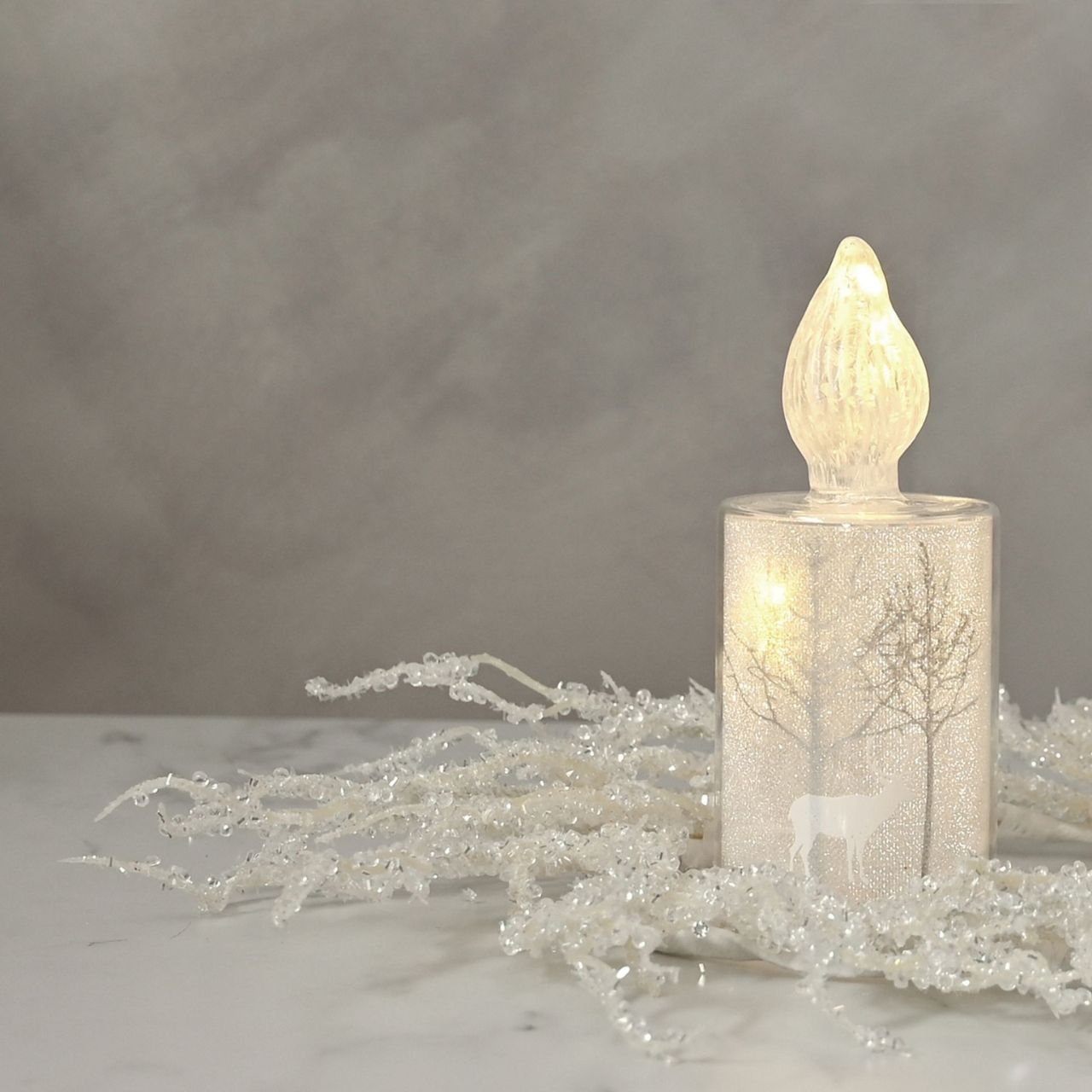 Christmas Silver Forest Scene Small LED Glass Candle Light A small silver forest scene LED candle-shaped light by THE SEASONAL GIFT CO. This glistening light will help to create a magical Winter Wonderland at home this festive period.