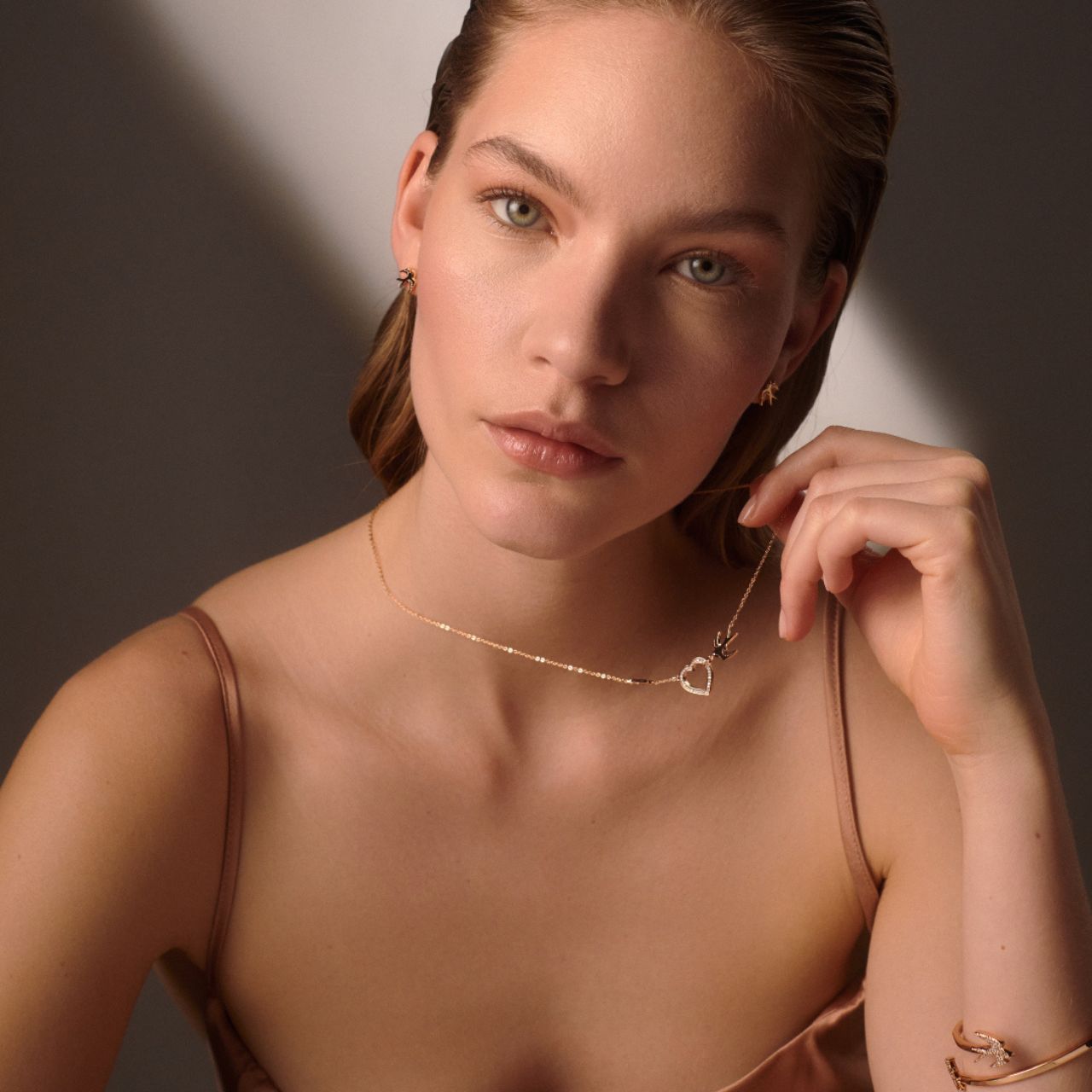The Swallow Pendant Heart and Swallows - Gold is a beautifully crafted piece that combines elegance with symbolic meaning. Featuring a delicate heart design adorned with two graceful swallows, this pendant represents love, freedom, and safe journeys.