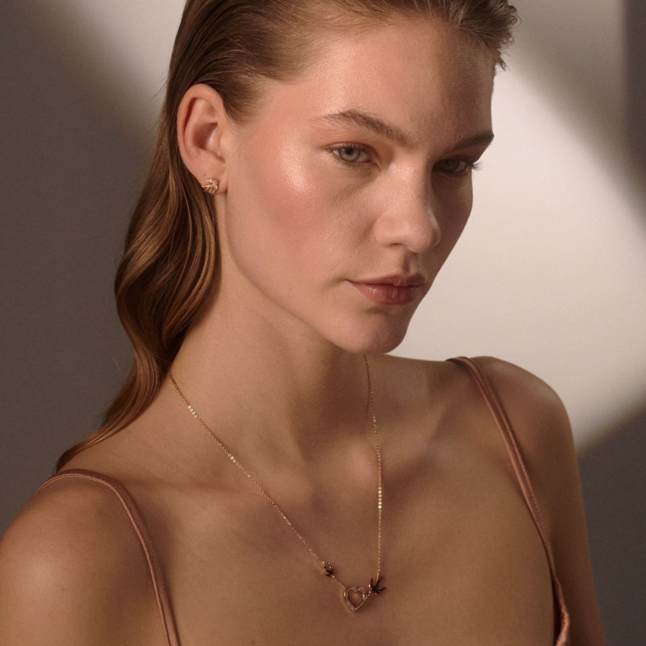 The Swallow Pendant Heart and Swallows - Gold is a beautifully crafted piece that combines elegance with symbolic meaning. Featuring a delicate heart design adorned with two graceful swallows, this pendant represents love, freedom, and safe journeys.