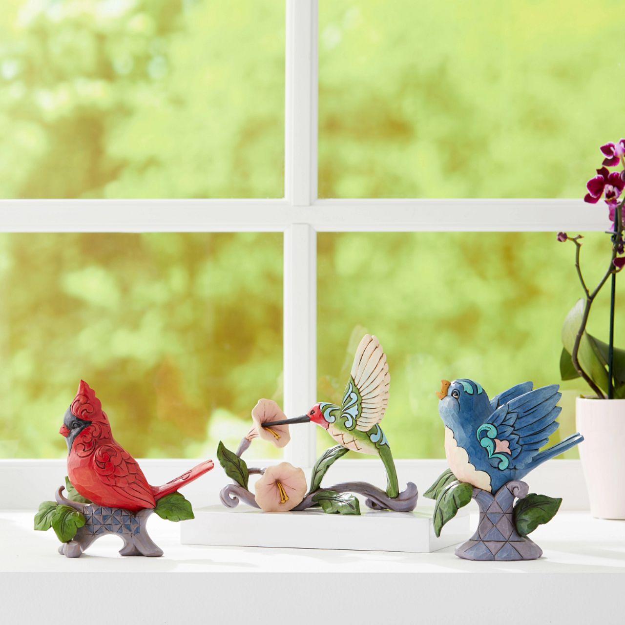 Jim Shore Heartwood Creek Blossoms and Beauty - Hummingbird with Flower  A colourful accent to brighten your day, Jim Shore's richly detailed Hummingbird design features a combination of subtle quilt patterning and beautifully hand-crafted rosemaling motifs. Each Heartwood Creek piece is hand painted, crafted using high quality cast stone. Comes in a branded Kraft gift box.