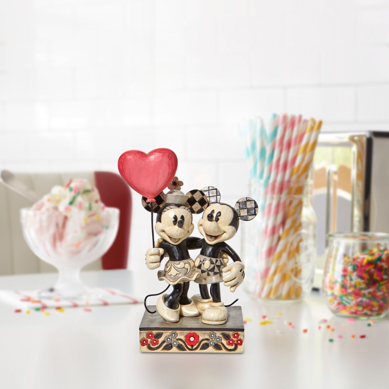 Jim Shore Disney Mickey and Minnie Heart Figurine "Love is in the Air" Celebrate love with the original Disney couple with this sweet relief by Jim Shore. Mickey Mouse hugs his girl close in this romantic figurine with classic Jim Shore rosemaling. Minnie holds on tight to a heart balloon and her valentine.