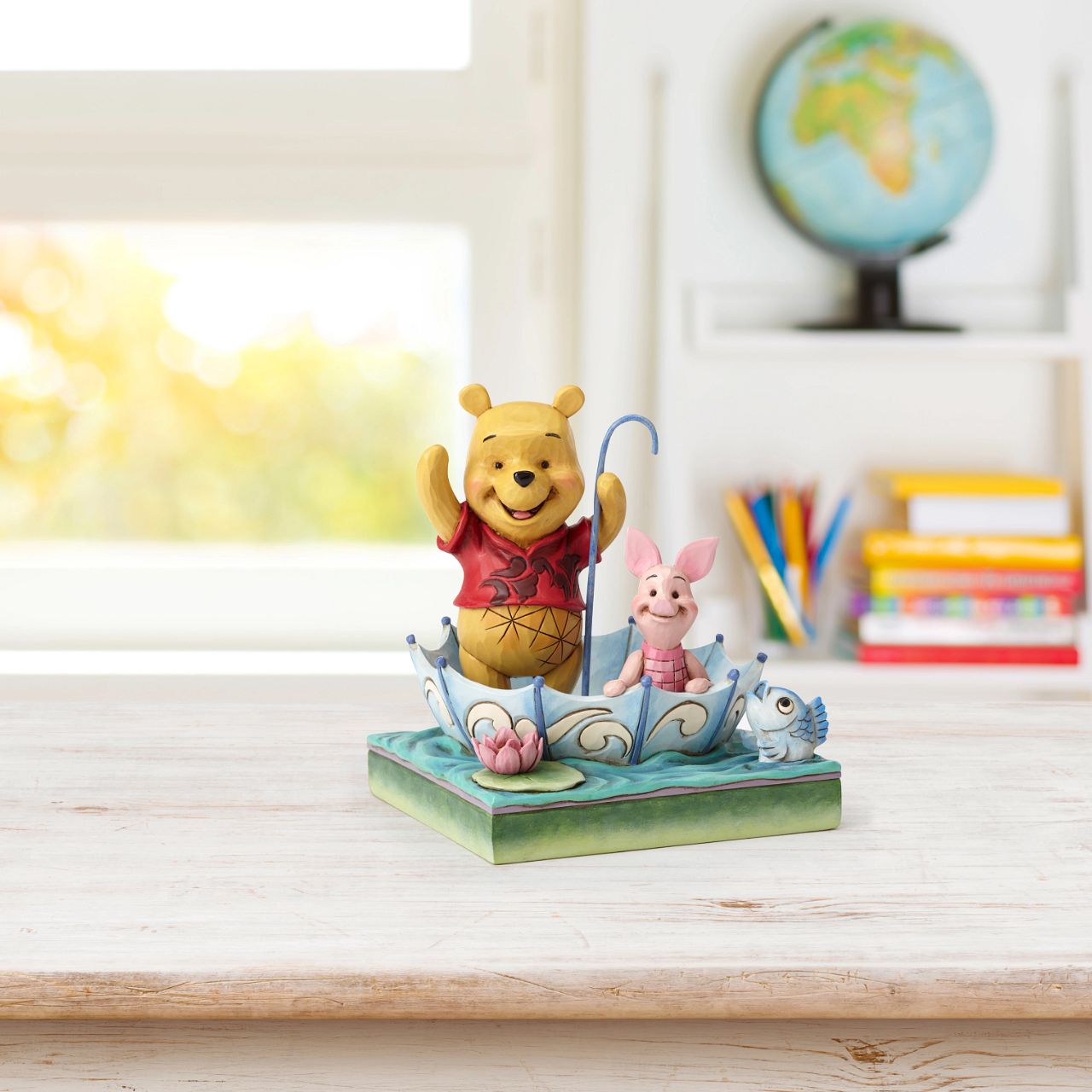 Jim Shore 50 Years of Friendship Winnie the Pooh and Piglet Figurine Winnie the Pooh and Piglet celebrate "50 Years of Friendship" while sharing smiles and an umbrella raft in this charming creation featuring the beloved Disney characters and the heartfelt style of folk artist Jim Shore.