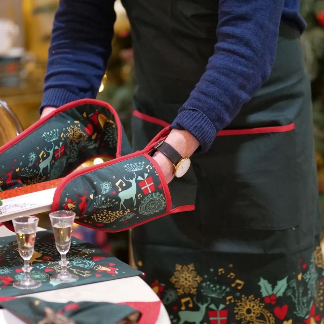 A Christmas Wish Double Oven Glove by Mindy Brownes Interiors A beautiful double oven glove finished in forest green with a Christmas design that depicts some of Christmas' key elements, such as reindeer, presents, music notes, and more.