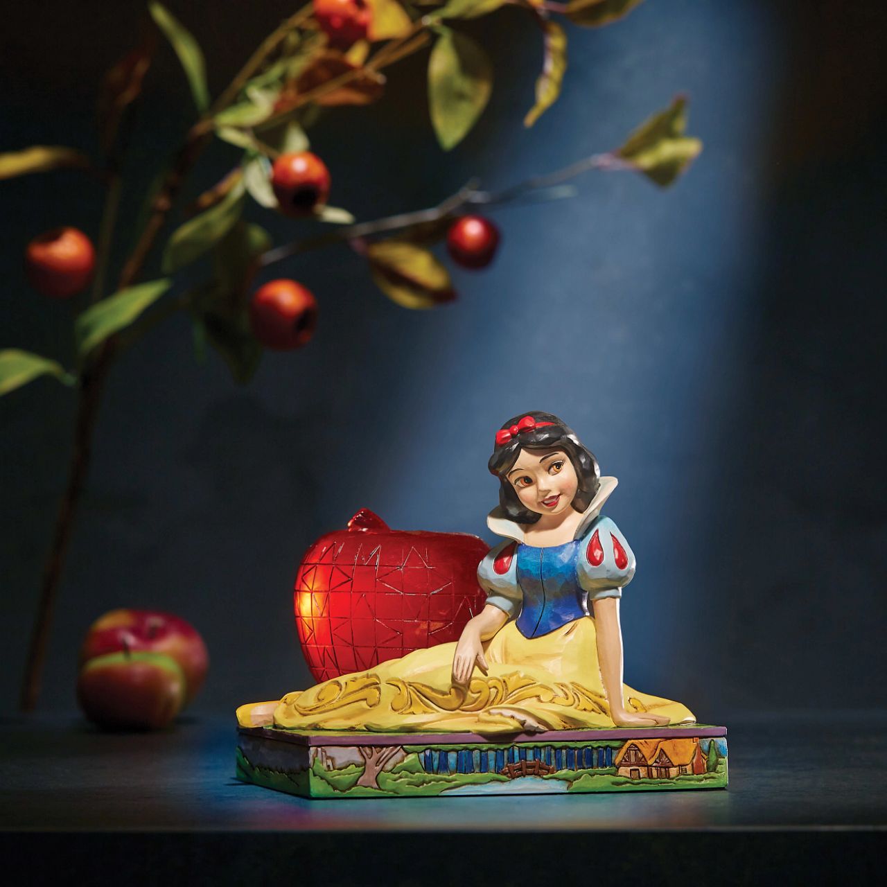 Jim Shore Disney Snow White with Apple Figurine  This Disney Traditions line by Jim Shore features iconic Walt Disney princesses with their famous props. With a base illustrating her story, this piece features Snow White in her famous gown next to a large apple. Packaged in a branded gift box.