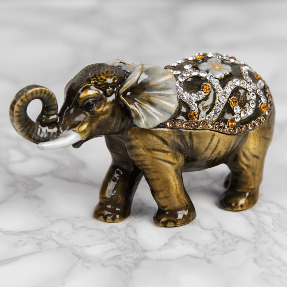 Treasured Trinkets - Elephant Curled Trunk A beautiful, hand painted and crystal finished elephant trinket box from Treasured Trinkets. Decorated with crystal patterns and floral embellishments, this colourful trinket box is a wonderful ornament to complement a mantelpiece, bookcase or cabine