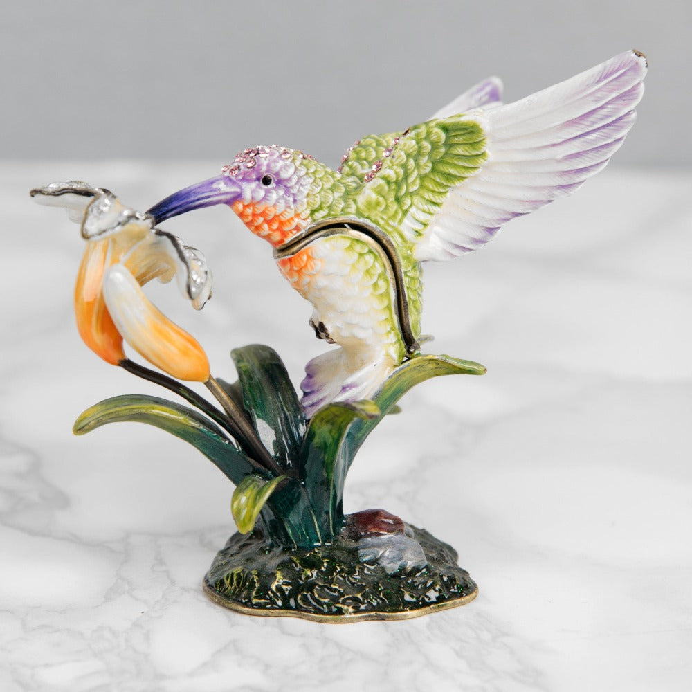 Treasured Trinkets Hummingbird A beautiful, hand painted and crystal finished hummingbird trinket box from Treasured Trinkets. Painted in the ethereal colours of a enchanting hummingbird, this trinket box is a wonderful ornament to complement a mantelpiece, bookcase or cabinet.
