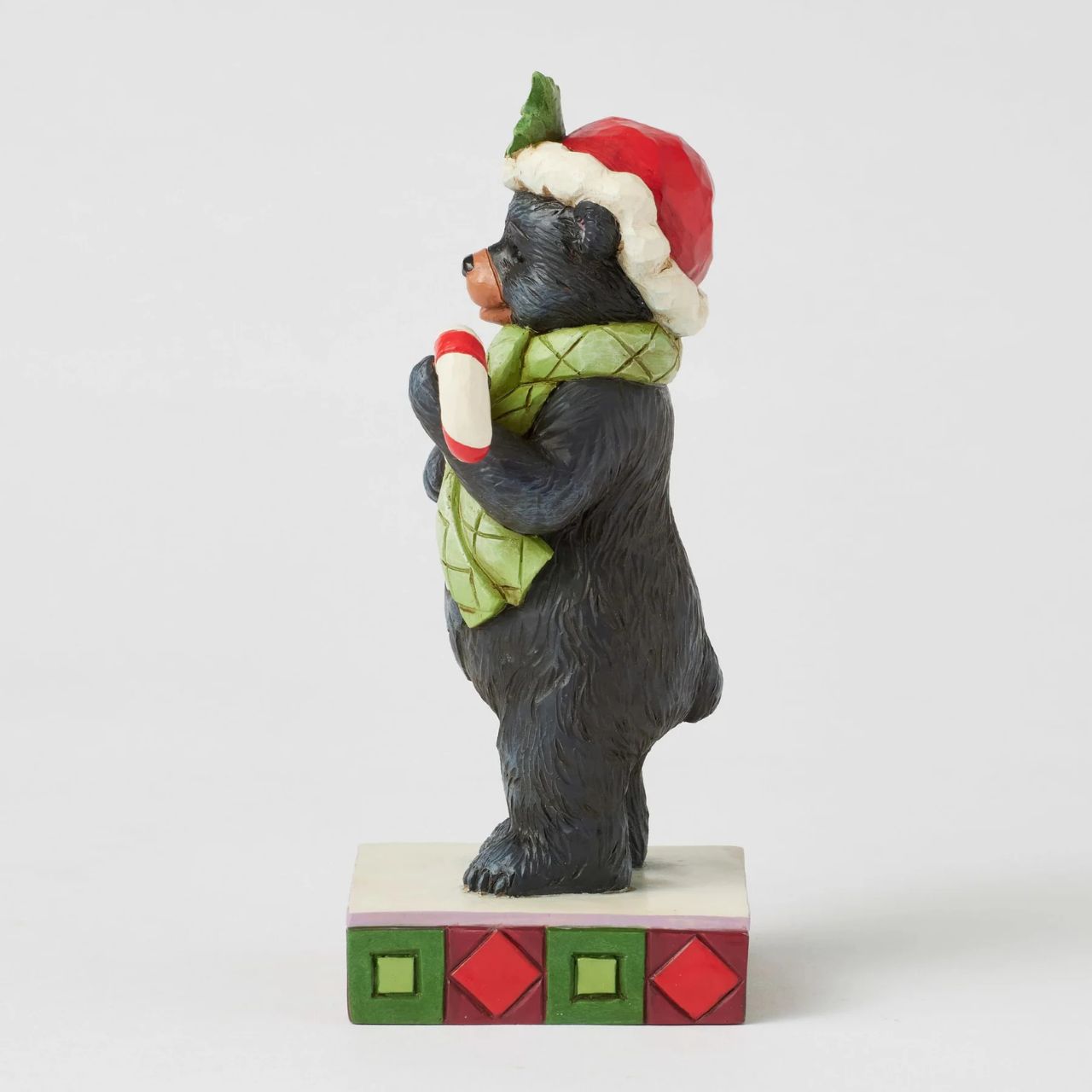 This playful Christmas at the Lodge Jim Shore black bear wears a festive Santa hat adorned with holly, he wears a festive scarf and holds a candy cane in his paws. With rosemaling designs on his fur, the piece brings sweet holiday fun and rustic charm to to any display.