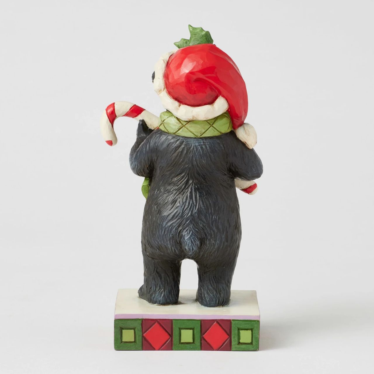 This playful Christmas at the Lodge Jim Shore black bear wears a festive Santa hat adorned with holly, he wears a festive scarf and holds a candy cane in his paws. With rosemaling designs on his fur, the piece brings sweet holiday fun and rustic charm to to any display.