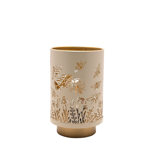 A decorative LED table lamp featuring delicate bee, honeycomb, and floral cut-out detailing. The soft neutral finish paired with warm gold accents creates a cosy, nature-inspired look.