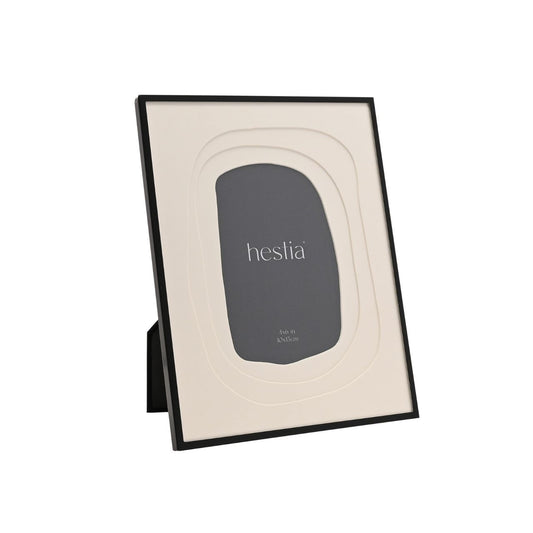 The Hestia Black Aluminium Photo Frame with Layered Mount is a striking piece for displaying memories. Its sleek black aluminium frame contrasts with the crisp white matte, highlighting the cherished 4x6 inch photograph at its centre.