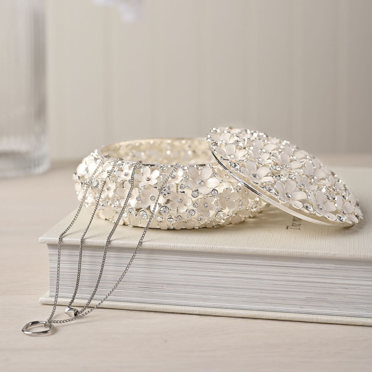 Indulge in the decadence of the Sophia Classic Daisy Open Work Trinket Box, a resplendent round piece adorned with shimmering crystals. This ornate jewel box, set against a crisp white backdrop, is an exquisite addition to any dressing table, radiating a unique charm.
