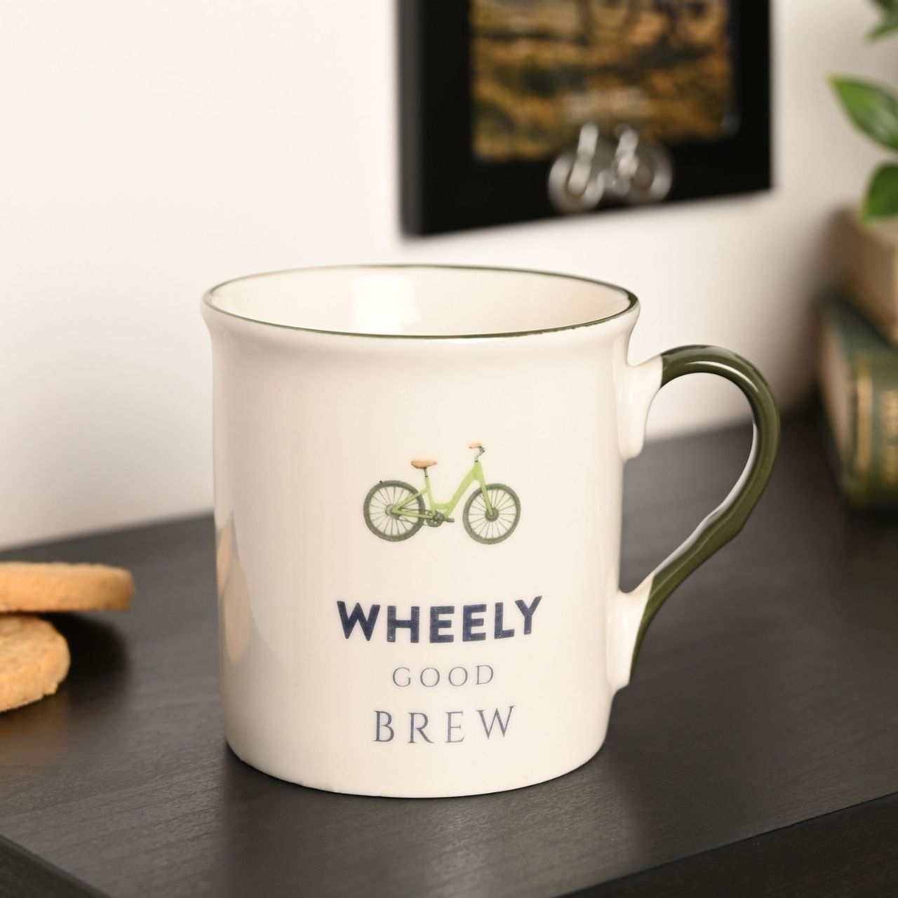 A white ceramic mug with a bicycle illustration and the text "Wheely Good Brew" printed on it.