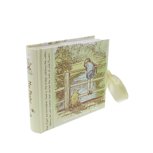 The album also reads: 'Pooh, Piglet and Christopher stood on the bridge watching the water, feeling the warm breeze that carried the smell of wild flowers.'