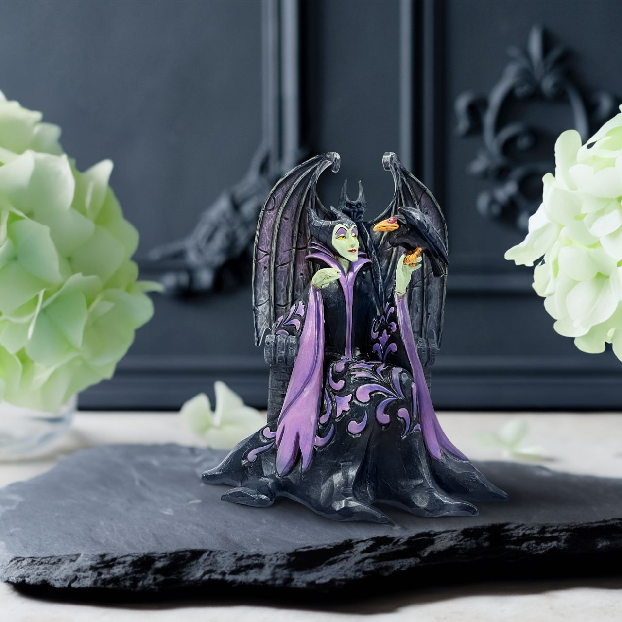 Maleficent sits atop her throne with her raven, Diavel. Dressed in her signature black with horned headdress, she is every piece the iconic villain from Sleeping Beauty. Designed by Jim Shore for his Disney Traditions collection.