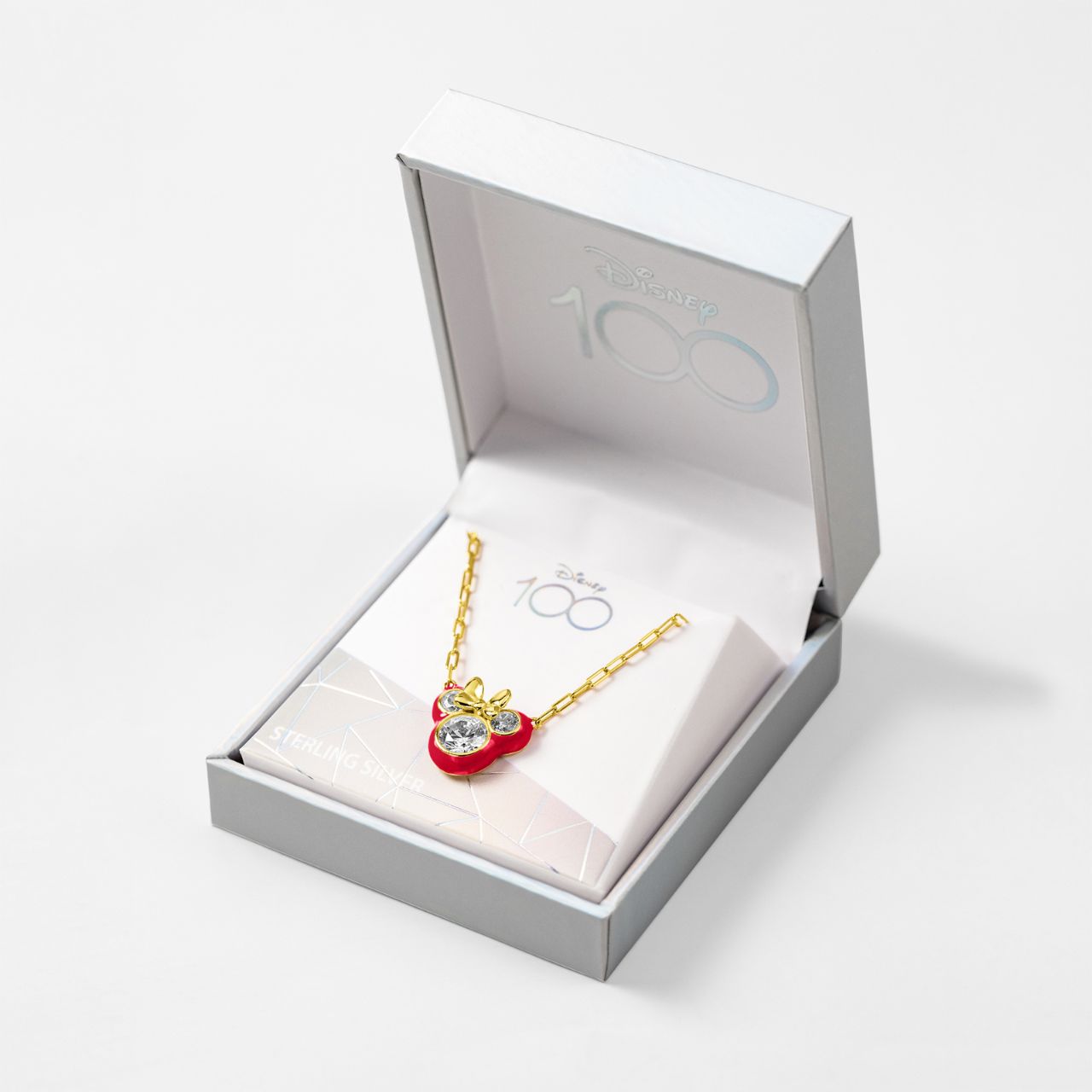 Disney 100th Anniversary Minnie Mouse Pink Back CZ Pendant  This Disney Minnie Mouse Pink Back Necklace features a stunning CZ pendant showcasing everyone's favourite mouse. With its delicate and stylish design, this necklace is the perfect accessory for any Disney fan. Add a touch of magic to your everyday look with this charming piece.