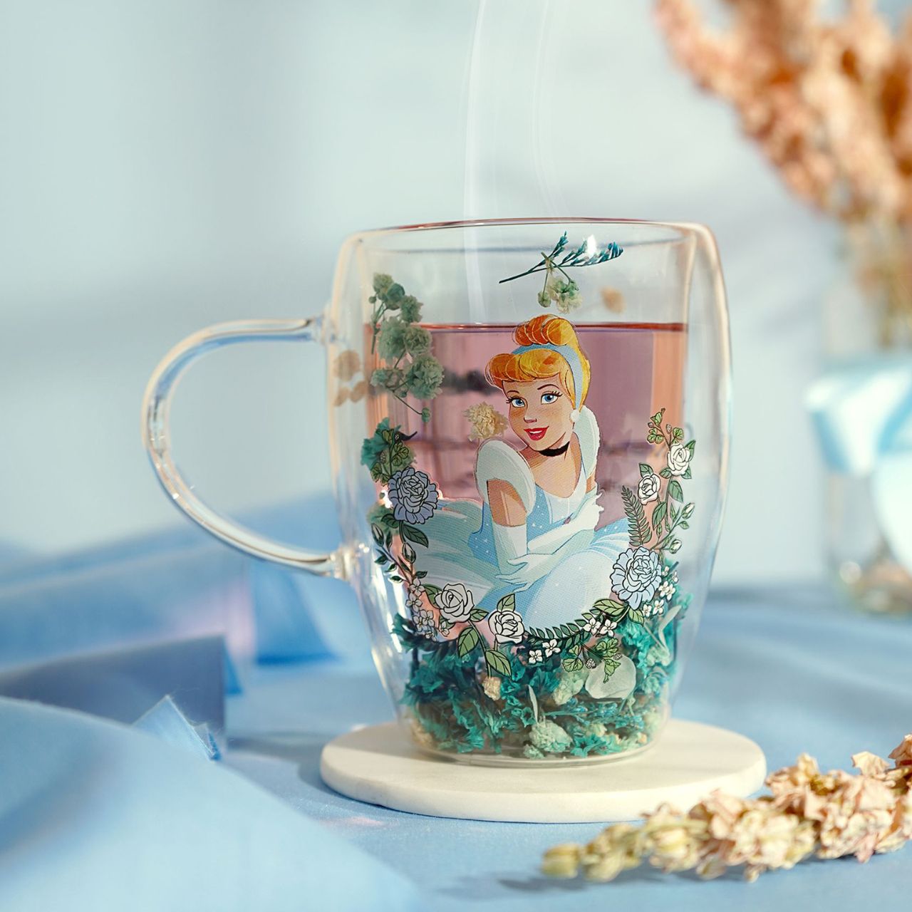 Step into the enchanting world of Disney with the Pastel Princess Glass Mug, adorned with a colourful illustration of Cinderella amidst a cascade of dried flowers.