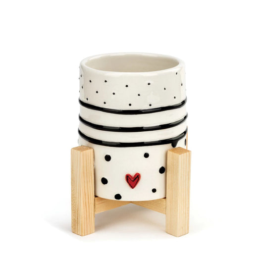 Tracy Pesche's Dots and Stripes Mini Planter  Add a whimsical, happy touch to your home with Tracy Pesche's uplifting ceramic art. Her hand-painted Dots and Stripes Mini Planter is a white planter with black rings and polka dots as well as small red hearts for a bright surprise.